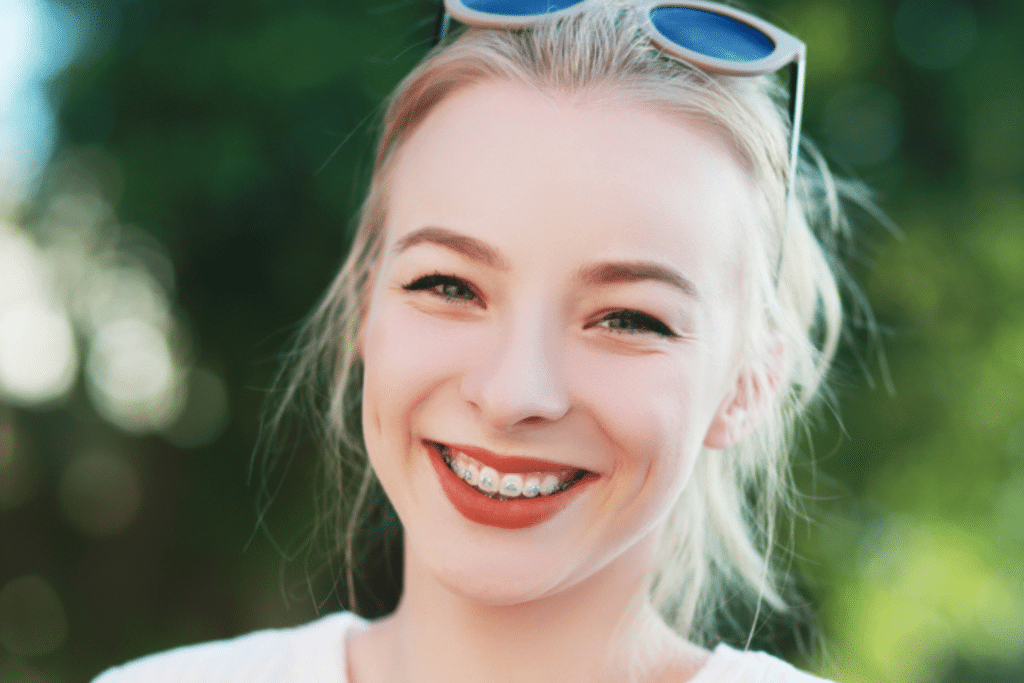 Smiling woman wearing metal braces outdoors with sunglasses on her head